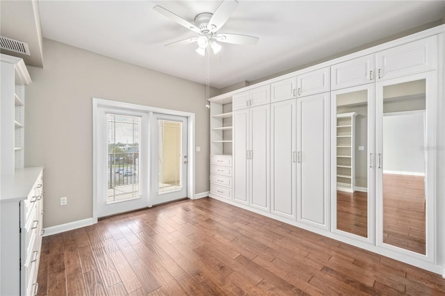 unfurnished bedroom with access to outside, wood finished floors, visible vents, and baseboards