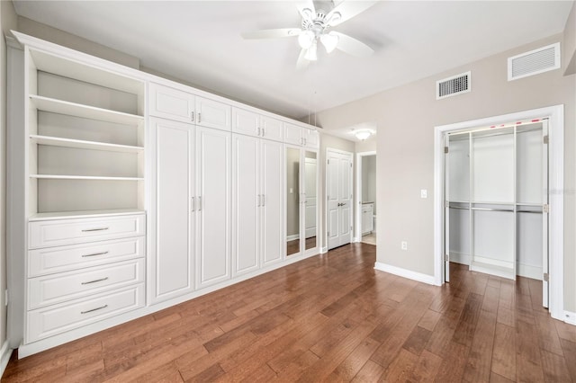 unfurnished bedroom featuring a ceiling fan, baseboards, visible vents, and wood finished floors