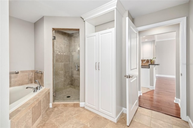 full bathroom featuring a stall shower, baseboards, a bath, and tile patterned floors