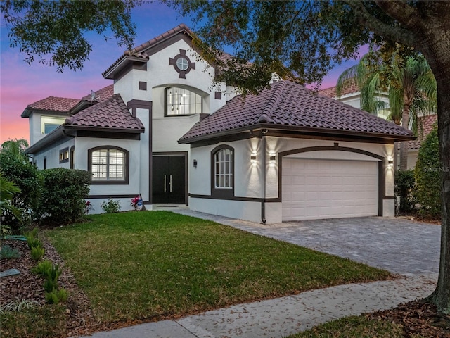 mediterranean / spanish home with a garage and a lawn