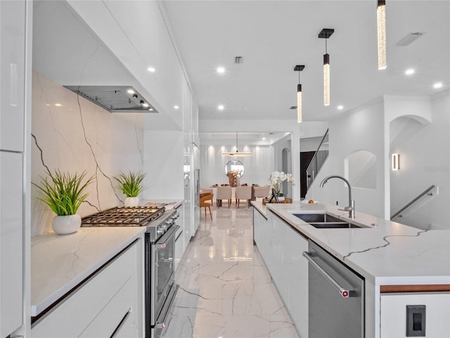 kitchen with sink, appliances with stainless steel finishes, light stone counters, white cabinets, and decorative light fixtures