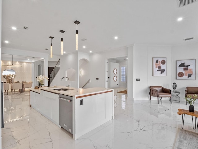 kitchen with pendant lighting, an island with sink, sink, white cabinets, and stainless steel dishwasher