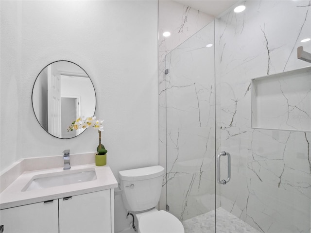 bathroom featuring vanity, a shower with shower door, and toilet