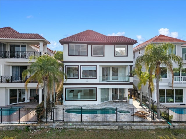 back of property with a fenced in pool and a patio