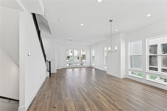 unfurnished living room with hardwood / wood-style flooring and a notable chandelier