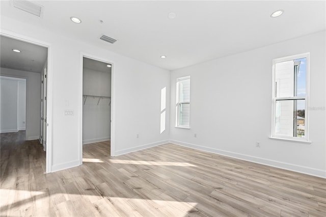 unfurnished bedroom with a walk in closet, light hardwood / wood-style flooring, and a closet