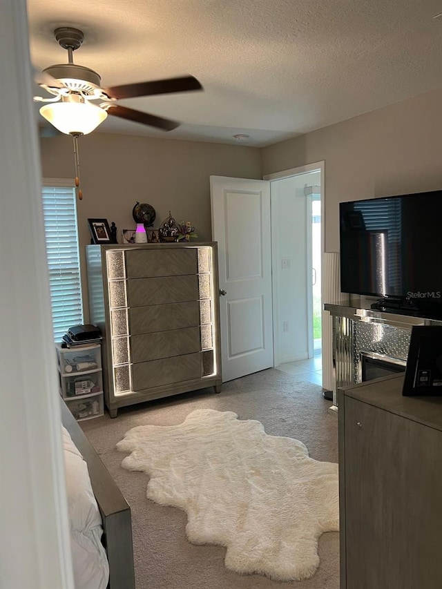 carpeted bedroom featuring ceiling fan and a textured ceiling