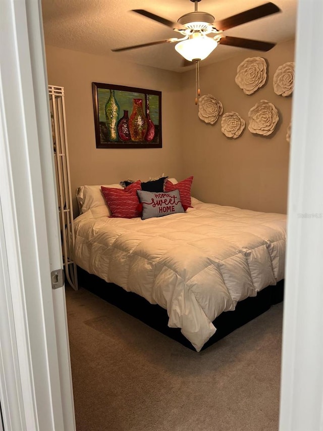 bedroom featuring ceiling fan, carpet floors, and a textured ceiling