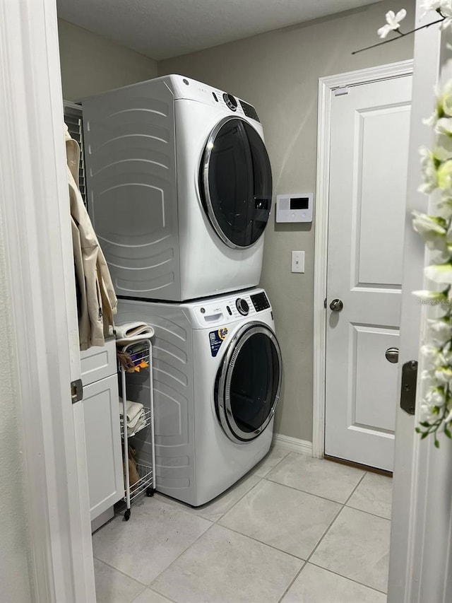 laundry room featuring stacked washer / dryer and light tile patterned floors