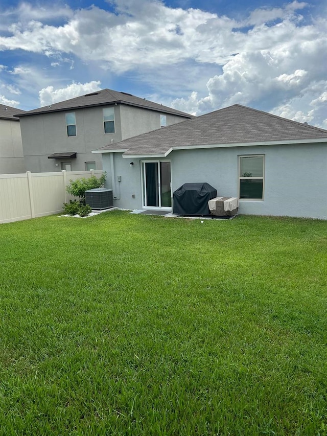 back of property featuring central AC and a yard