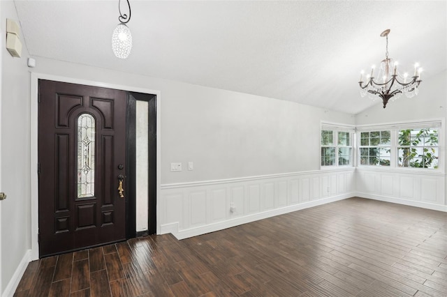 entryway with lofted ceiling, dark wood-type flooring, and a notable chandelier