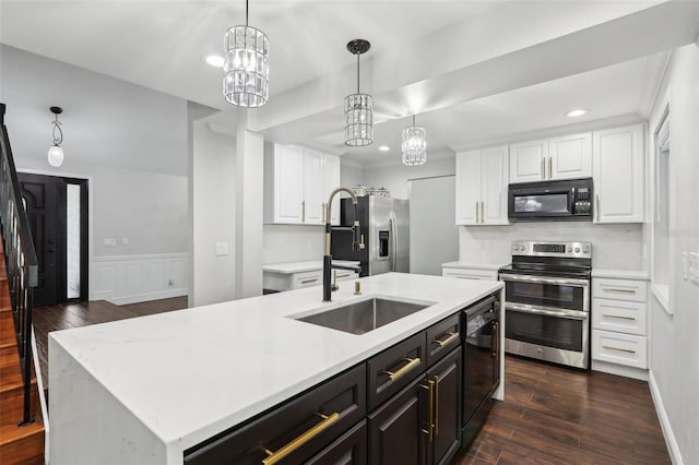 kitchen with a kitchen island with sink, pendant lighting, white cabinets, and black appliances