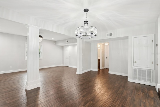 unfurnished living room with a notable chandelier, decorative columns, and dark hardwood / wood-style floors