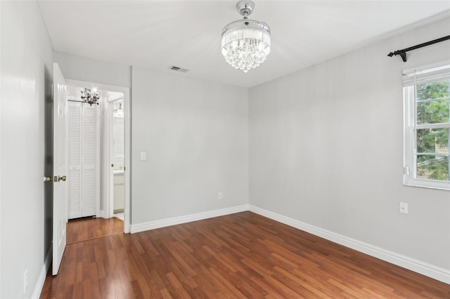 unfurnished bedroom with dark wood-type flooring and an inviting chandelier