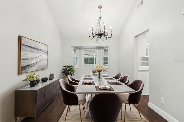 dining space with hardwood / wood-style flooring, lofted ceiling, and a chandelier