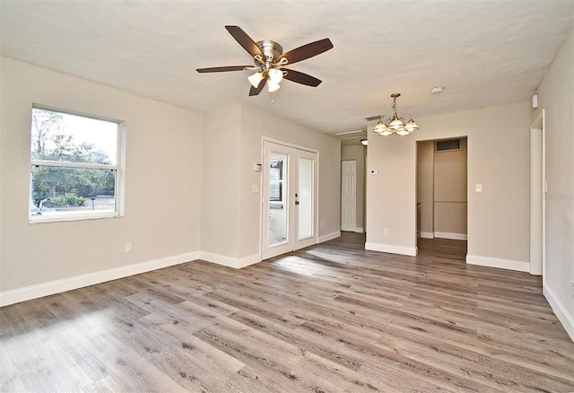 spare room featuring hardwood / wood-style flooring, ceiling fan with notable chandelier, and french doors