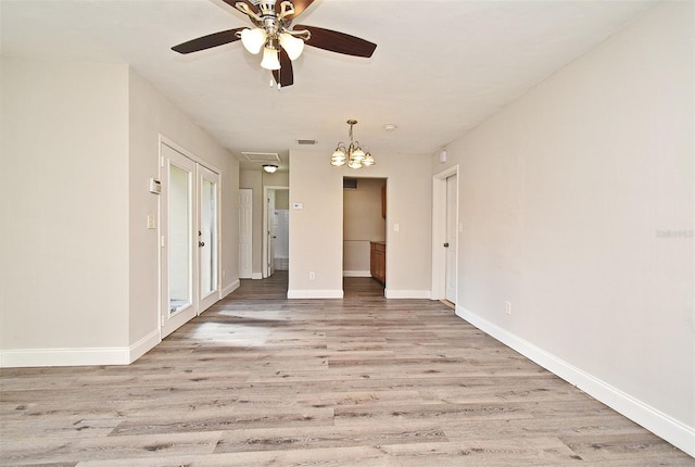 spare room with ceiling fan with notable chandelier and light hardwood / wood-style flooring