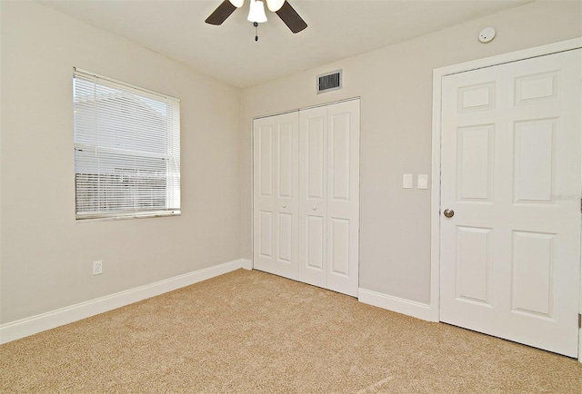 unfurnished bedroom with ceiling fan, light colored carpet, and a closet