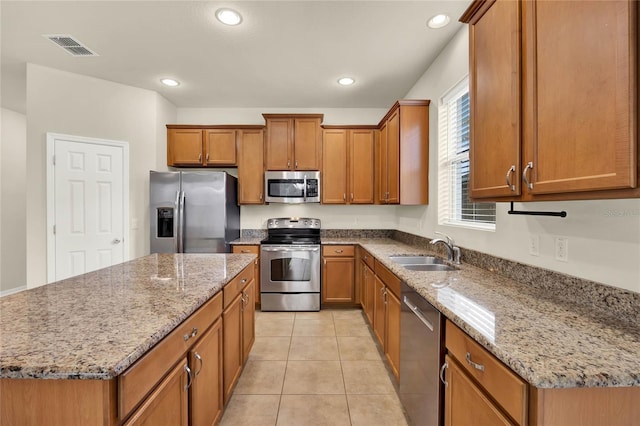 kitchen featuring appliances with stainless steel finishes, sink, a center island, light tile patterned floors, and light stone countertops