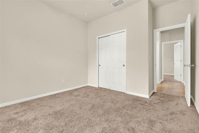 unfurnished bedroom featuring light carpet and a closet