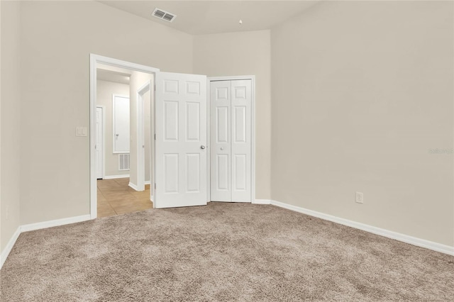 unfurnished bedroom featuring light colored carpet and a closet