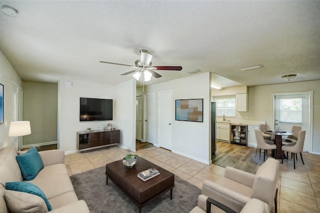 living room featuring wine cooler, ceiling fan, sink, and light tile patterned floors