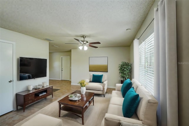 living room with ceiling fan, light tile patterned floors, and a textured ceiling