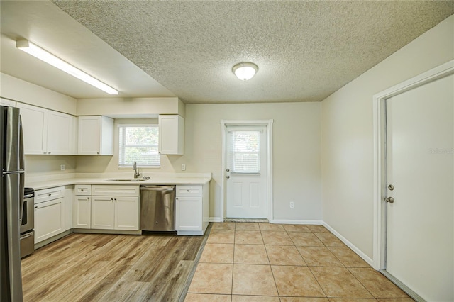 kitchen featuring white cabinetry, sink, stainless steel appliances, and a textured ceiling