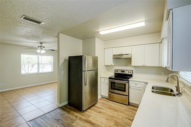 kitchen with sink, appliances with stainless steel finishes, white cabinetry, light hardwood / wood-style floors, and a textured ceiling