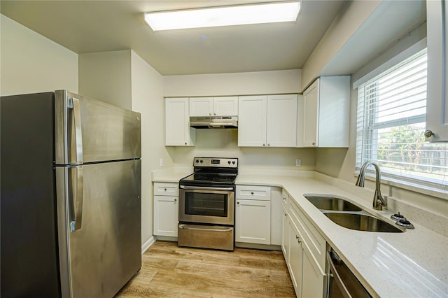 kitchen featuring sink, white cabinetry, light wood-type flooring, appliances with stainless steel finishes, and light stone countertops