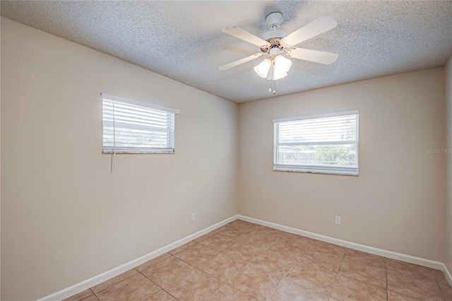 spare room with ceiling fan, a textured ceiling, and light tile patterned floors