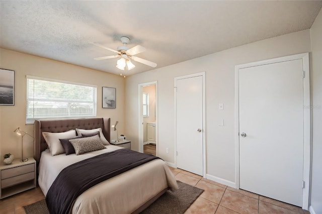 tiled bedroom with connected bathroom, a textured ceiling, and ceiling fan