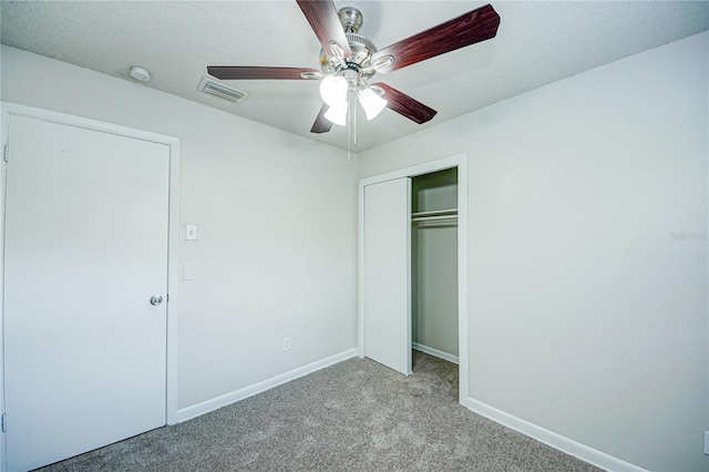 unfurnished bedroom with a textured ceiling, light colored carpet, a closet, and ceiling fan