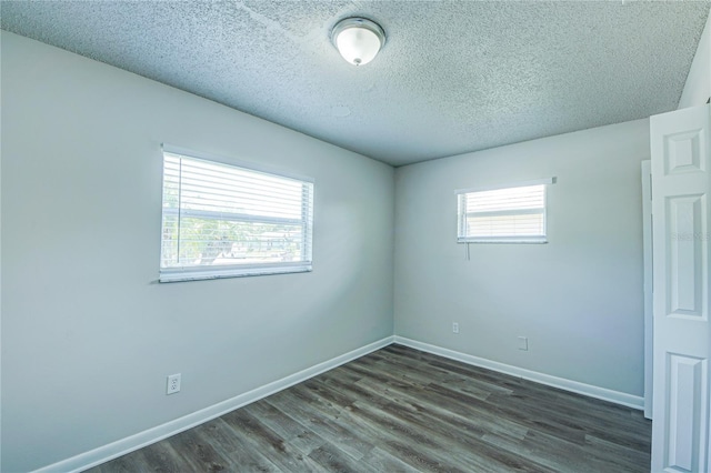 spare room with a textured ceiling, dark hardwood / wood-style floors, and a healthy amount of sunlight