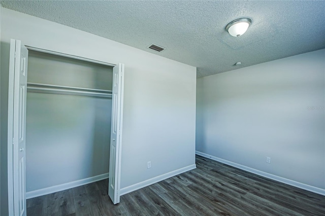 unfurnished bedroom with a closet, dark hardwood / wood-style floors, and a textured ceiling