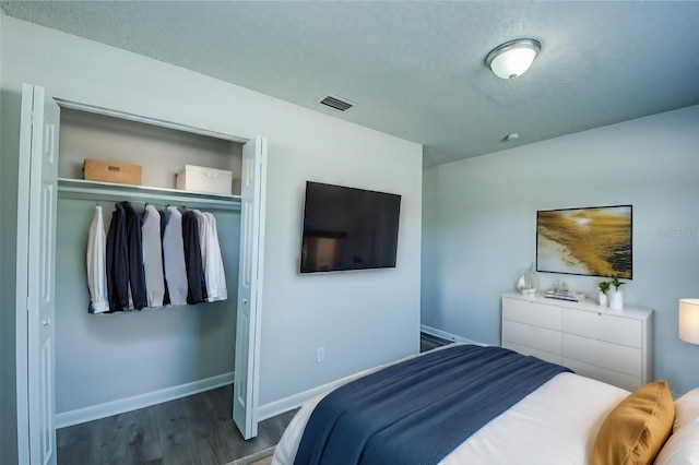 bedroom with a textured ceiling, dark hardwood / wood-style flooring, and a closet