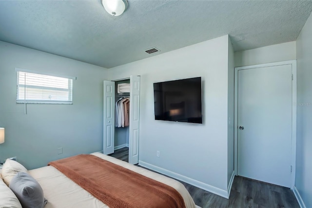 bedroom with dark wood-type flooring, a textured ceiling, and a closet