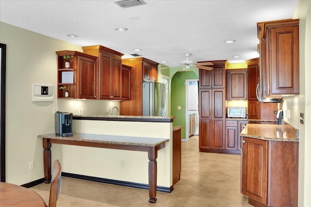 kitchen featuring stainless steel appliances, ceiling fan, a kitchen breakfast bar, and kitchen peninsula