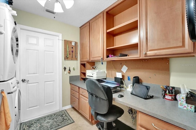 tiled office featuring stacked washer / drying machine and built in desk