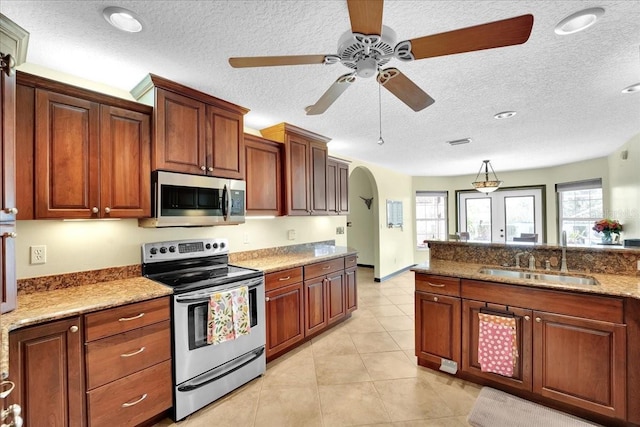 kitchen with pendant lighting, sink, light tile patterned floors, appliances with stainless steel finishes, and light stone counters