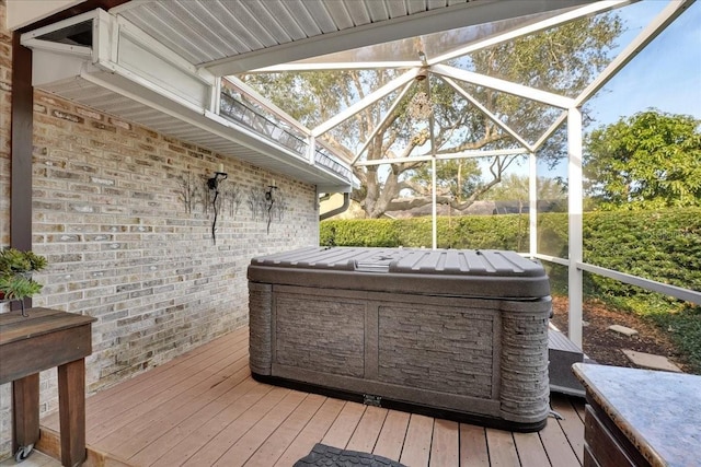 wooden deck featuring a lanai and a hot tub