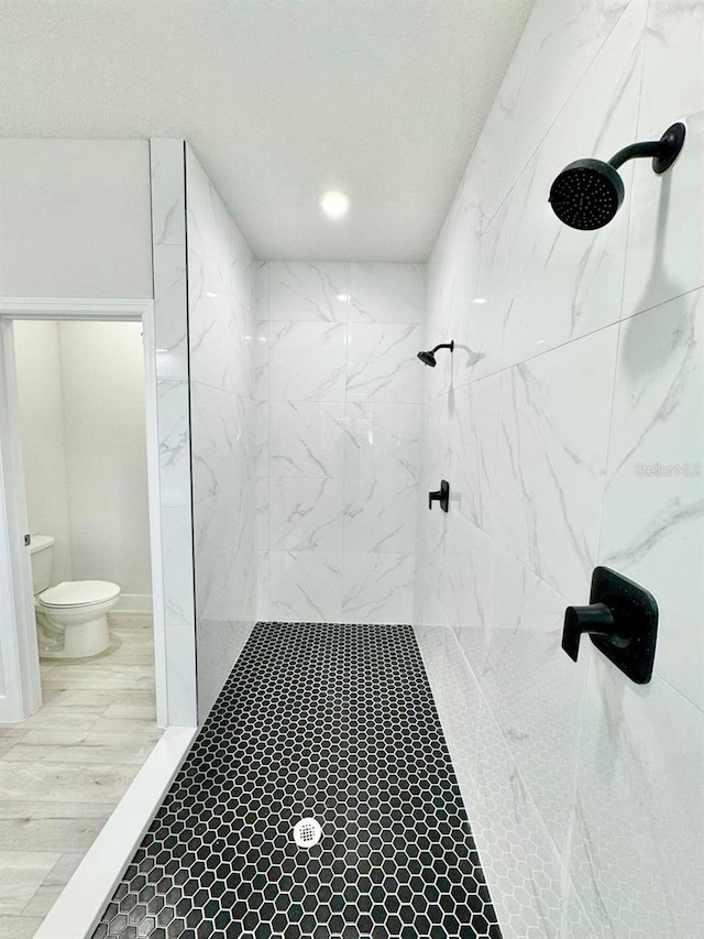 bathroom featuring a tile shower and toilet