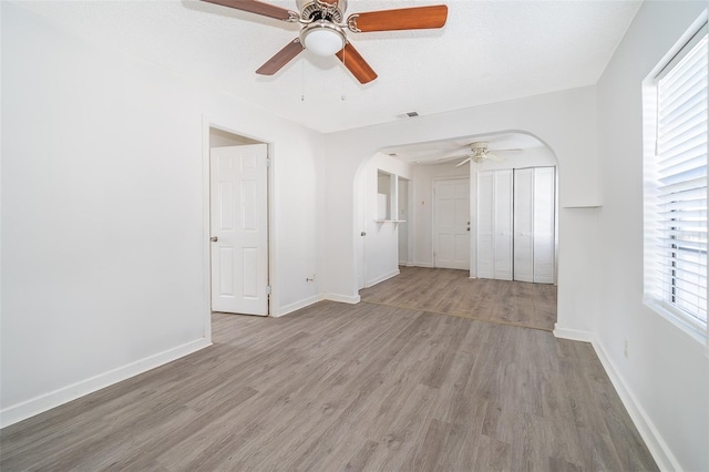 empty room with ceiling fan, a textured ceiling, and light wood-type flooring