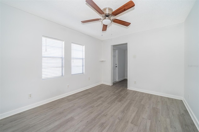 empty room with ceiling fan, a textured ceiling, and light wood-type flooring