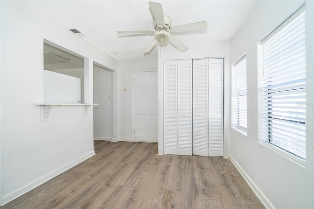 unfurnished bedroom with hardwood / wood-style flooring, ceiling fan, a textured ceiling, and a closet