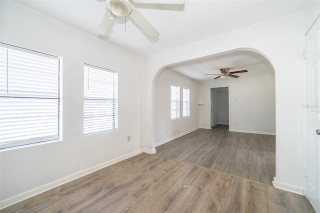 empty room featuring ceiling fan, wood-type flooring, and a textured ceiling