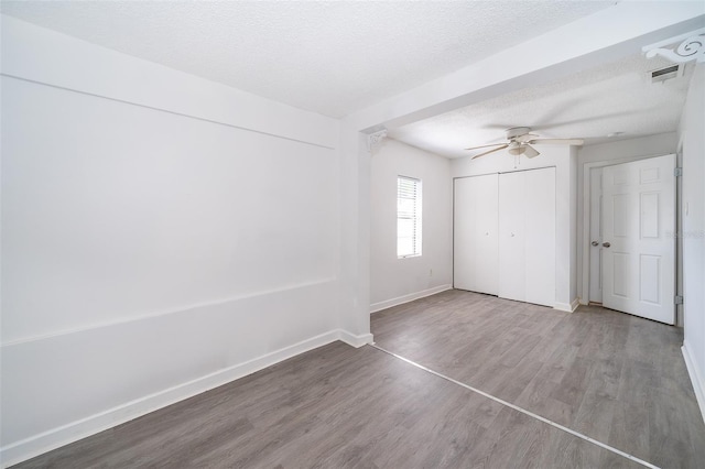 unfurnished bedroom with wood-type flooring, ceiling fan, a textured ceiling, and a closet