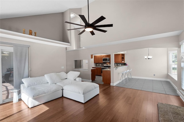 living room with lofted ceiling, ceiling fan with notable chandelier, and dark hardwood / wood-style flooring