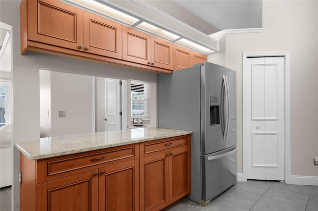 kitchen with light stone counters, stainless steel fridge with ice dispenser, kitchen peninsula, and light tile patterned flooring