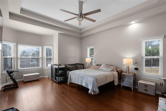 bedroom featuring dark hardwood / wood-style floors, a raised ceiling, and a textured ceiling